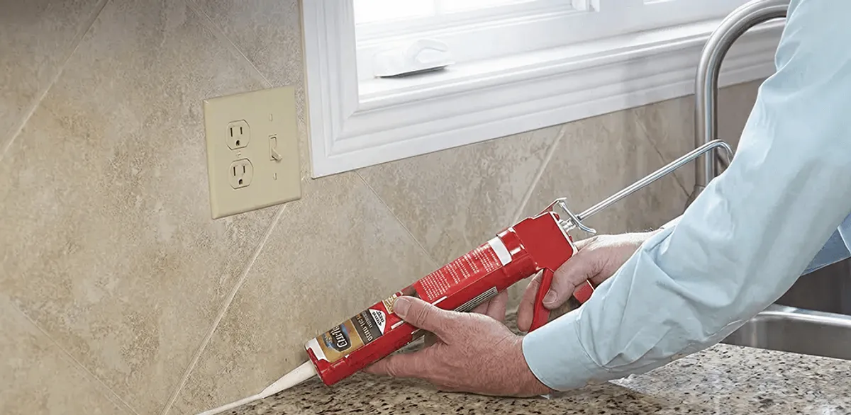Handyman applying caulk along a kitchen backsplash and countertop seam in Oakland, CA
