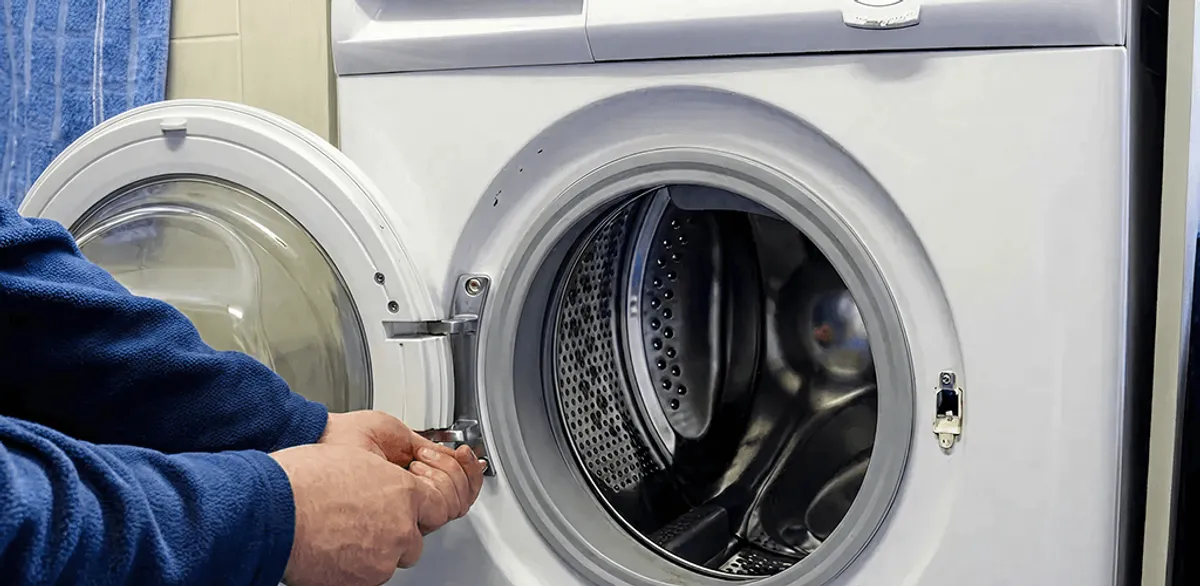 Washing machine repair handyman checking a front-load washer door and latch in Oakland, CA