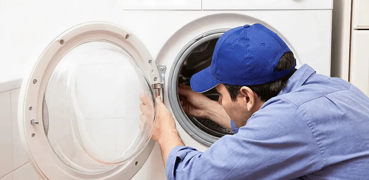 Washing machine repair handyman inspecting a front-load washer drum in Oakland, CA